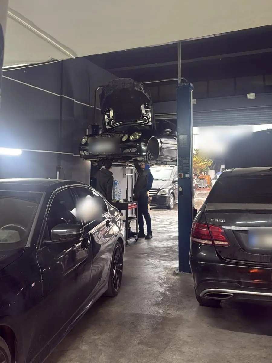 Lift üzerinde kaldırılmış Mercedes'in altında çalışan iki teknisyen